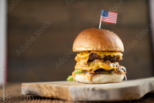 Fourth of July celebration. American flag and decorations. Burgers on rustic wooden table.