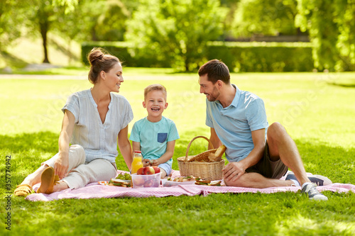 family, leisure and people concept - happy mother, father and little son having picnic at summer park © Syda Productions