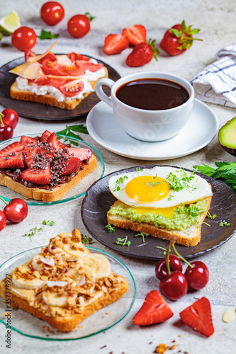 Breakfast different toasts with berries  cheese  egg and fruit  gray background. Breakfast table concept.