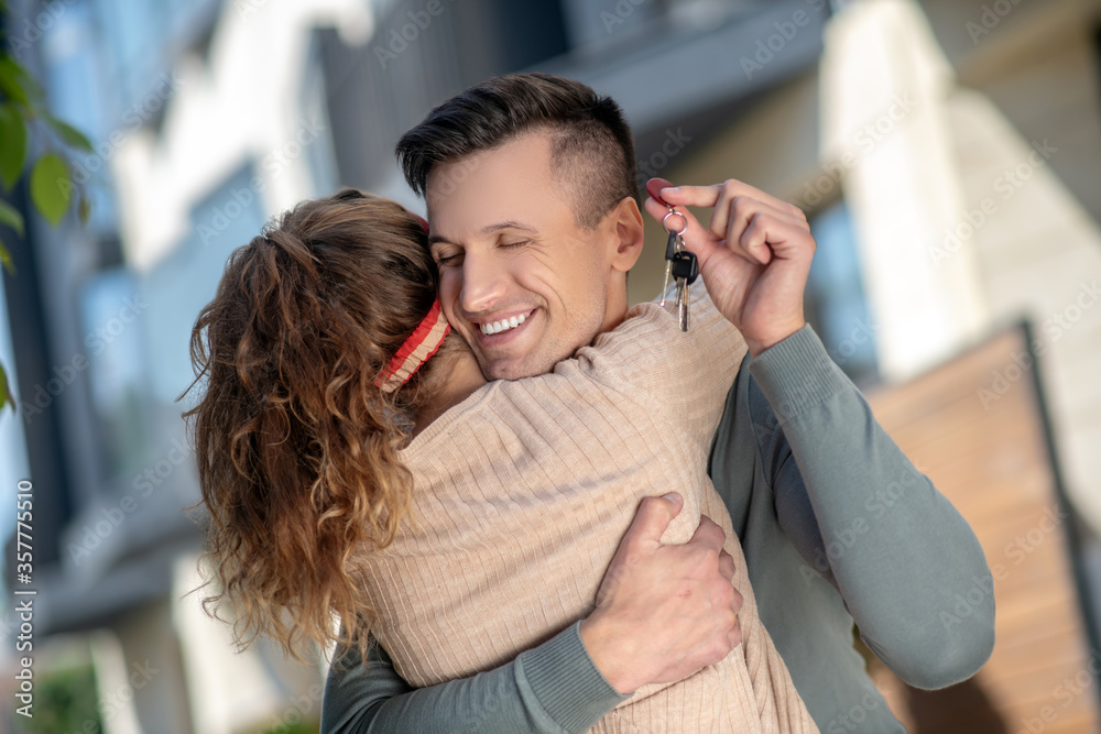 Young couple holding the key from new house and hugging Young couple holding the key from new house and hugging