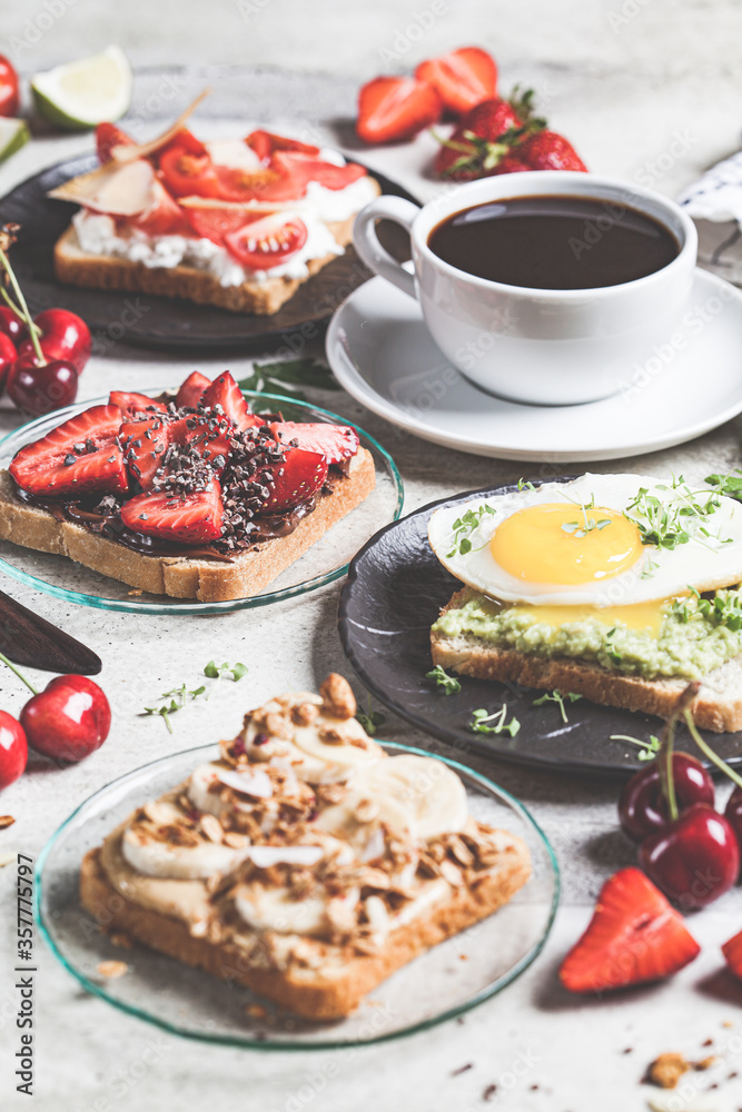 Breakfast different toasts with berries, cheese, egg and fruit, gray background. Breakfast table concept.