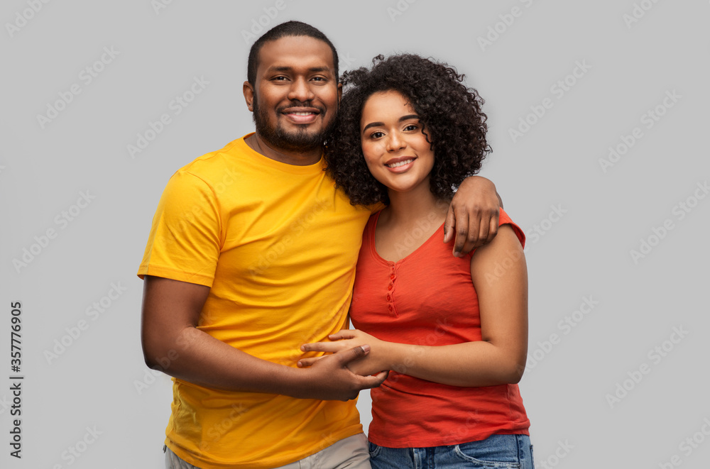 Obraz premium relationships and people concept - happy african american couple hugging over grey background