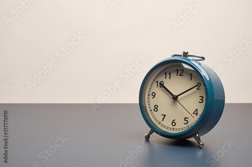 Retro alarm clock on dark blue table and white wall background with copy space.