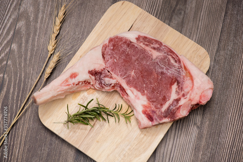 Raw Tomahawk steak on a wooden background with rosemary
