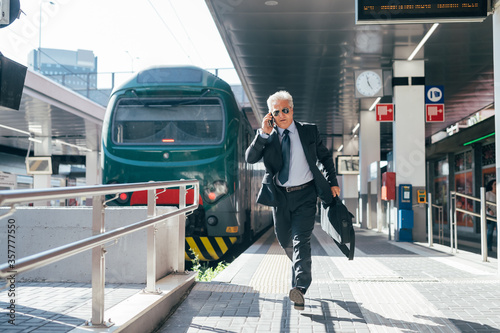 Professional senior businessman running railway station - Businessman late for work running on train platform
