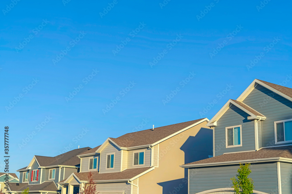 Homes with horizontal wall sidings and front gable roofs againts clear blue sky Homes with horizontal wall sidings and front gable roofs againts clear blue sky