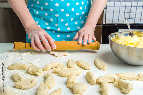 Cooking vegetarian dumplings with mashed potatoes (kreplach, jewish ravioli) in home kitchen. Step 8 female hands roll out a dough circles dough with a rolling pin. Step by step instruction
