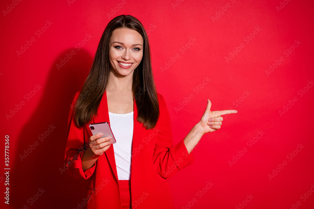 Naklejka premium Photo of attractive business lady successful worker browsing telephone directing finger side empty space recommending sale offer wear blazer suit isolated bright vivid red color background