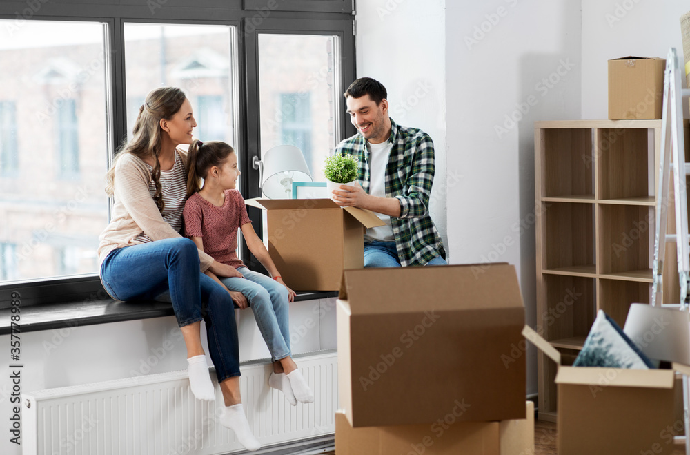 mortgage, family and real estate concept - happy mother, father and little daughter with stuff in boxes moving to new home mortgage, family and real estate concept - happy mother, father and little daughter with stuff in boxes moving to new home