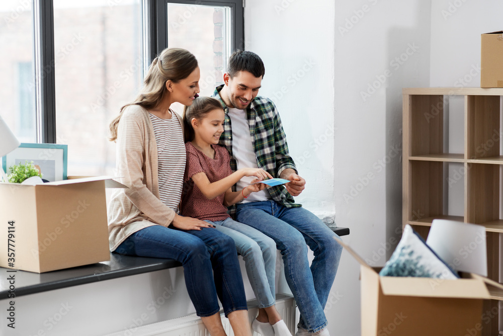 mortgage, family and real estate concept - happy mother, father and little daughter with color palette and stuff in boxes moving to new home