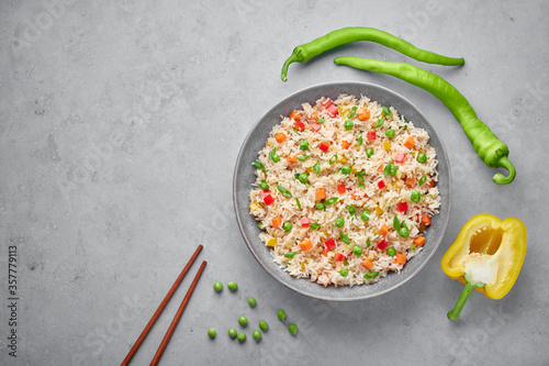 Veg Fried Rice in gray bowl on concrete table top. Veg Fried rice is indo chinese cuisine dish. Indian vegetarian meal. Asian food. Copy space. Top view