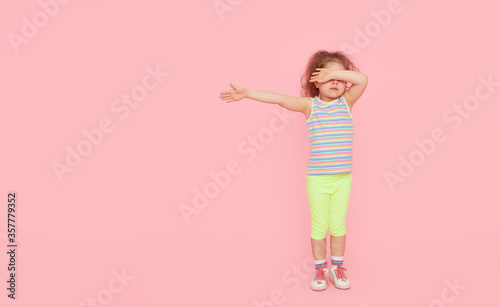 Challenges for children. Child girl model in full growth on a pink studio background. empty space for inscription