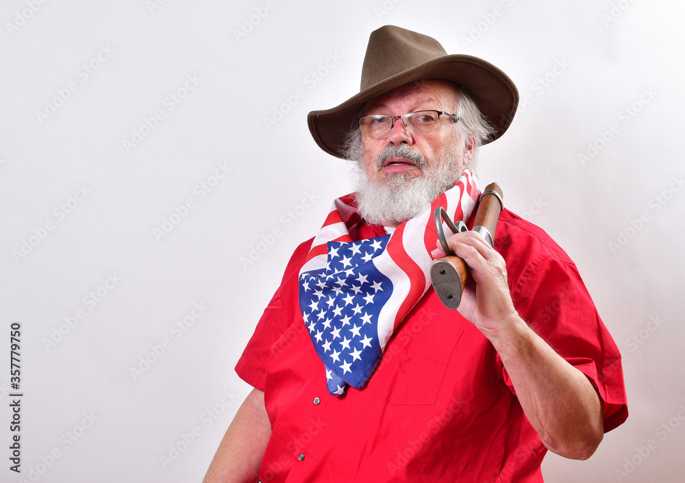Serious looking man, armed with a sawed off rifle, wearing patriotic colors, eyeglasses and a floppy western hat. - obrazy, fototapety, plakaty 