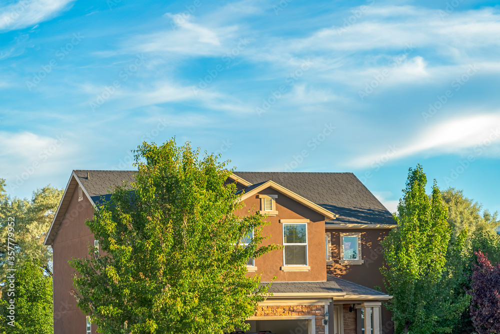 Home surrounded by abundant green trees with blue sky background on a sunny day