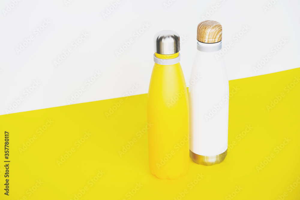 Stylish reusable eco-friendly stainless steel thermo bottles on yellow background. Stylish reusable eco-friendly stainless steel thermo bottles on yellow background.