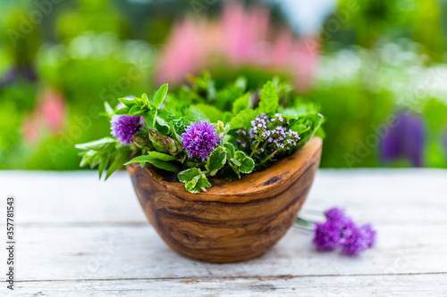 Fresh herbs in a wooden mortar.