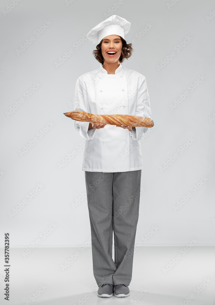 cooking, culinary and bakery concept - happy smiling female chef or baker in toque holding french bread or baguette over grey background cooking, culinary and bakery concept - happy smiling female chef or baker in toque holding french bread or baguette over grey background