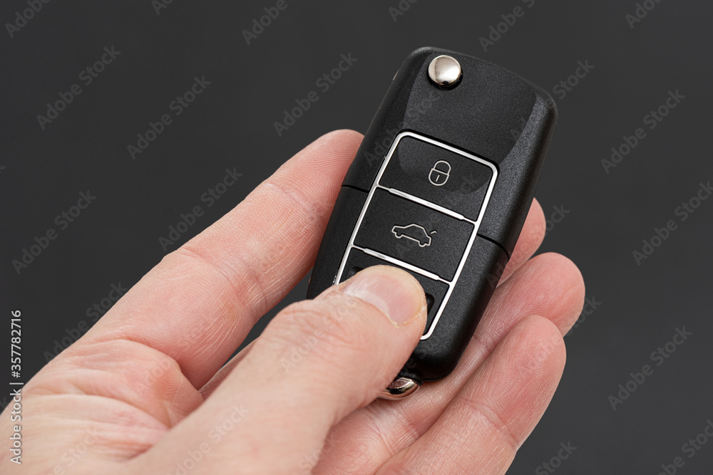 Man hand holding a car key remote on the black background. Man hand holding a car key remote on the black background.