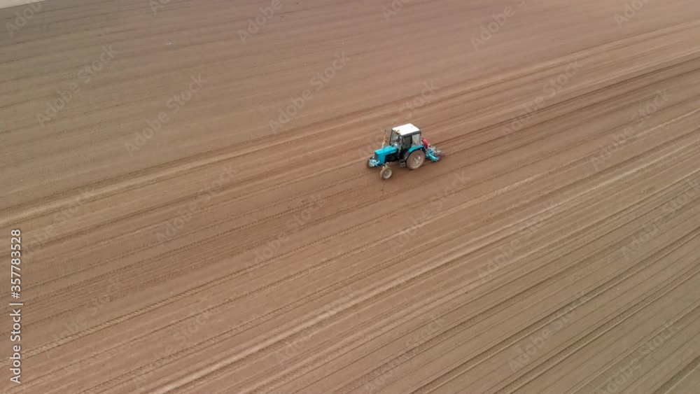 Agriculture and agribusiness, a modern tractor sows the field with grain crops using a seed drill attached to the tractor on the ground Agriculture and agribusiness, a modern tractor sows the field with grain crops using a seed drill attached to the tractor on the ground