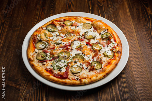 Bacon, mushroom and pickles nourishing pizza with sour cream sauce, wooden background, low key