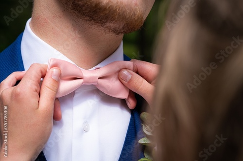 Fotografie, Obraz Closeup shot of a female holding the pink bow tie of the male