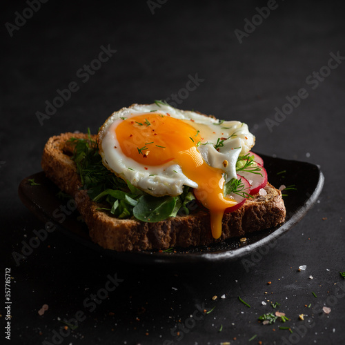 Dark photo of sandwich with fryied egg photo