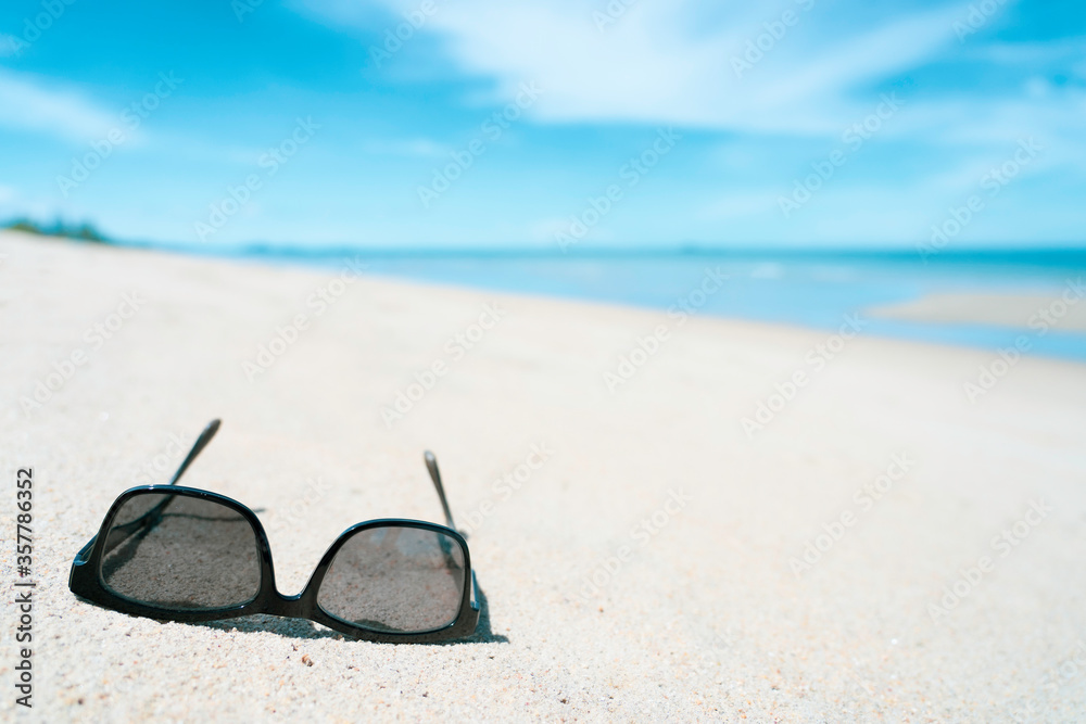 Sunglass on white sand beach with turquoise colour sea in summer sunny day time