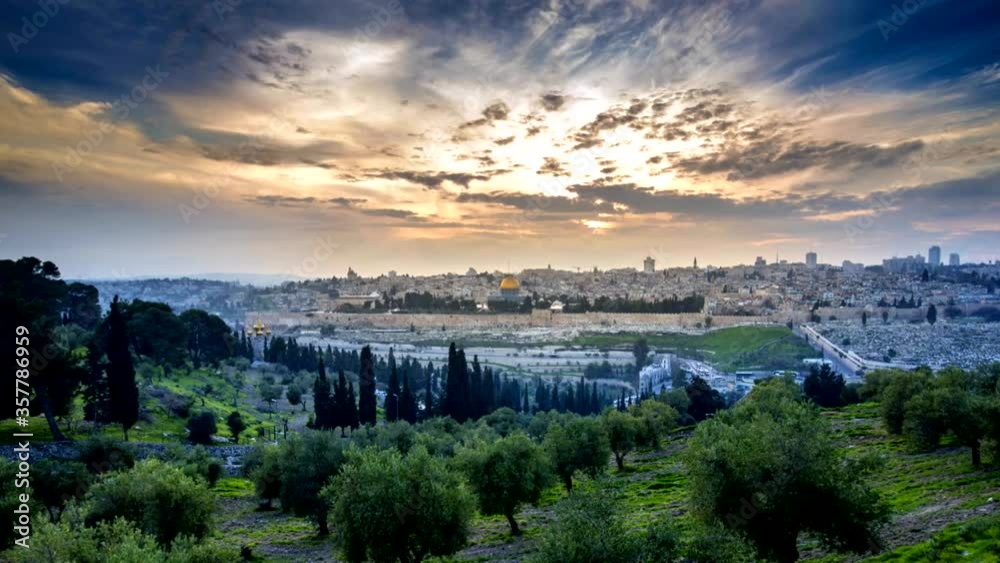 Dramatic sunset time lapse of Jerusalem's Old City, view from the Mount of Olives over the Dome of the Rock and the Temple Mount, with an olive grove in the foreground; Jerusalem Israel