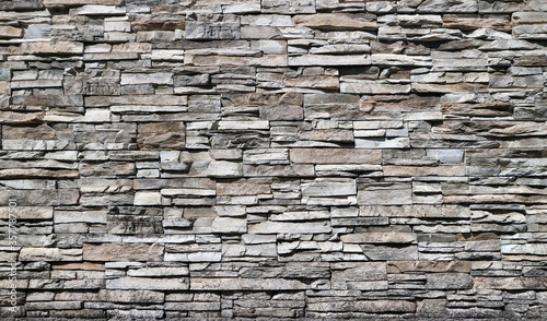 Stone cladding wall made of striped stacked bricks of natural brown and gray rocks . 