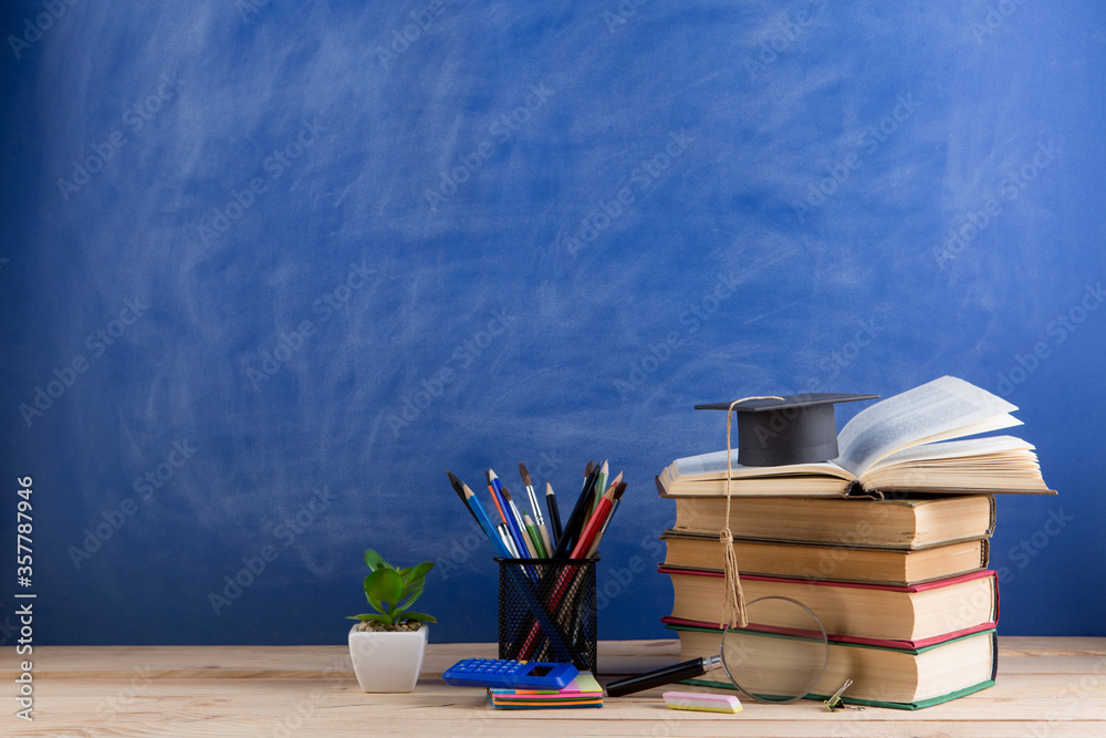 Education and sciences concept - books on the teacher desk in the auditorium, chalkboard on the background.