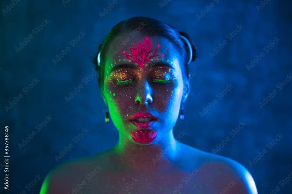 Portrait of painted woman in fluorescent powder and paint. Colorful, interesting and unusual shoot.