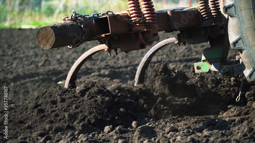 The tractor cultivates and cuts furrows in the field. Tractor work in the black soil field in the village