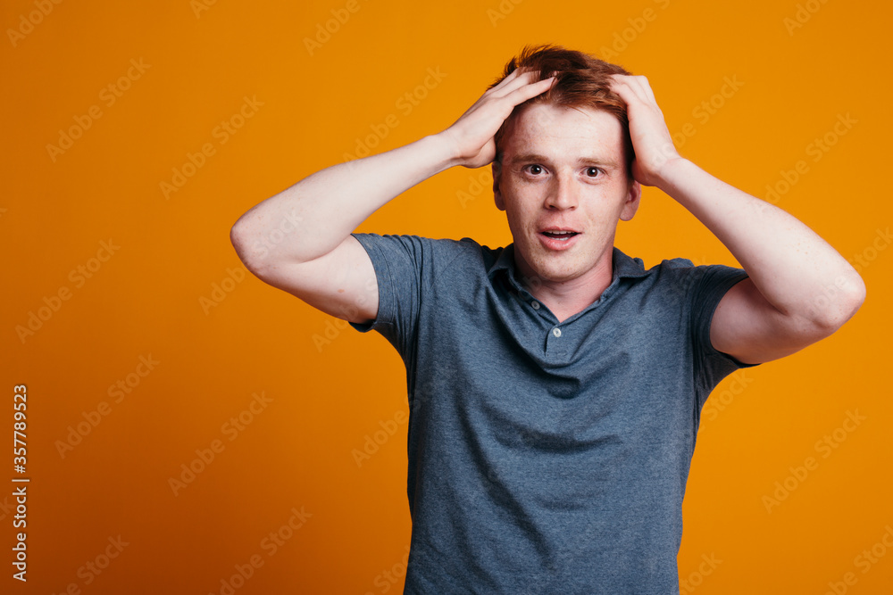 The guy with red hair is fascinated by the camera and clasps his hands in surprise. The young man holds hands hair. The guy with red hair is fascinated by the camera and clasps his hands in surprise. The young man holds hands hair.