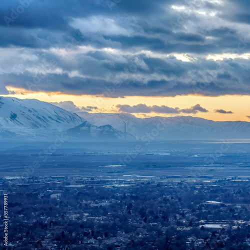 Square frame Salt Lake City Utah landscape against snowy mountain and cloudy sky at sunset