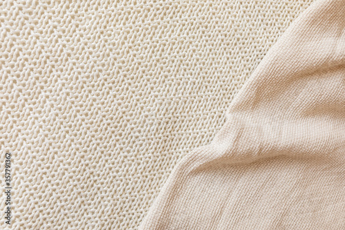 Two soft beige knitted blankets lying diagonally with copy space. Retro abstract boho scandinavian rustic background with cloth for decorative design. Cosy warm seasonal interior concept.