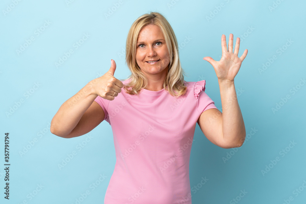 Fototapeta premium Middle age woman isolated on blue background counting six with fingers