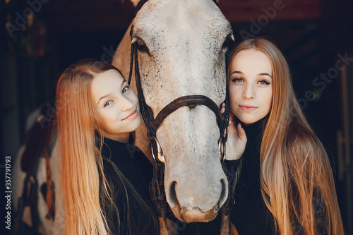 Girls with a horse. Women in a ranch. Blonde in a black sweater