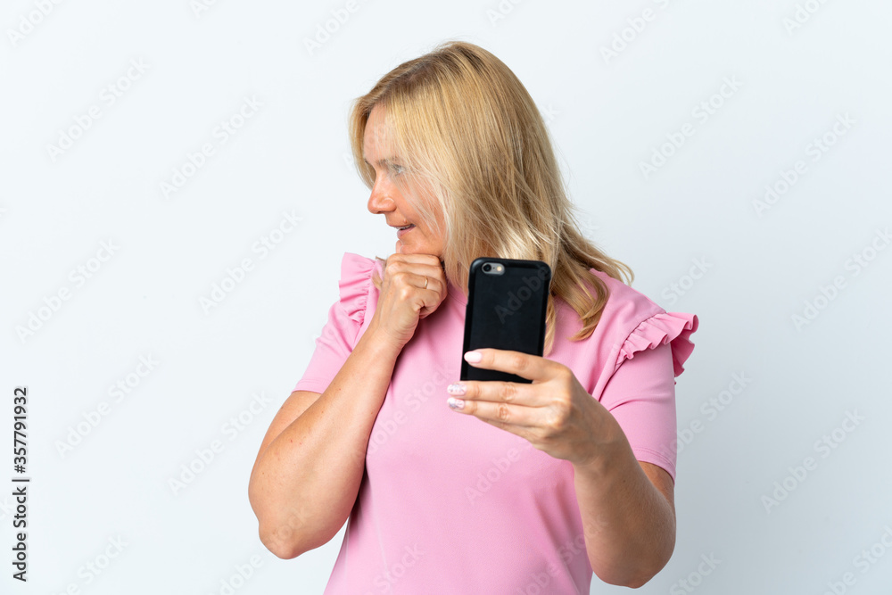 Fototapeta premium Middle age using mobile phone isolated on white background thinking an idea and looking side