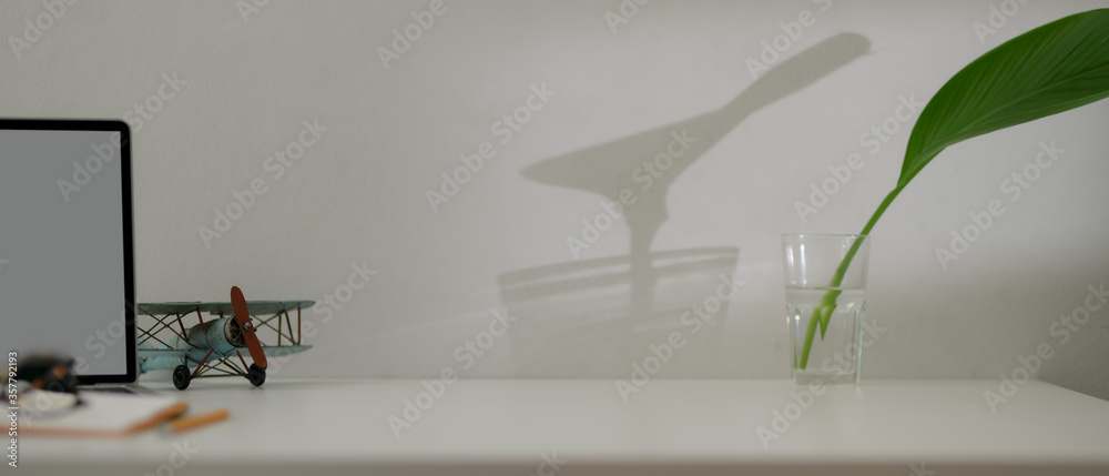 Obraz premium Copy space on minimal worktable with blank screen laptop, schedule book, decoration, and plant in a glass vase