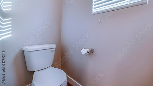 Panorama Toilet at the corner of a bathroom against gray wall with tissue roll holder photo