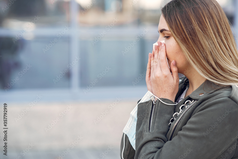 Woman in the city. Person in a mask. Coronavirus theme. Runny nose.