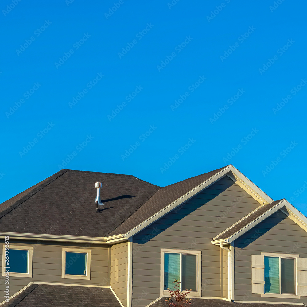 Square Home exterior with view of the upper storey agaist clear blue sky background Square Home exterior with view of the upper storey agaist clear blue sky background