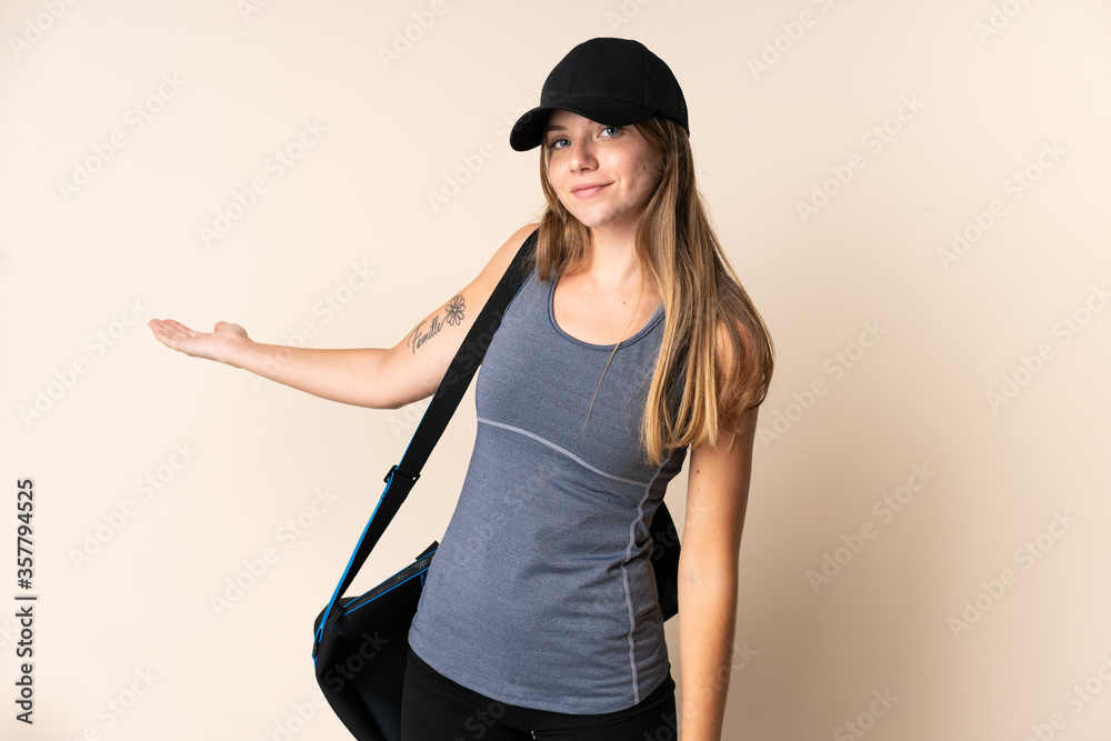 Young sport Lithuanian woman holding a sport bag isolated on beige background extending hands to the side for inviting to come Young sport Lithuanian woman holding a sport bag isolated on beige background extending hands to the side for inviting to come