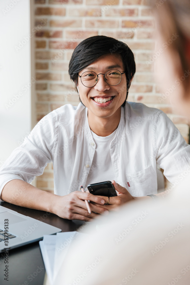 Image of joyful asian man laughing and talking with college Image of joyful asian man laughing and talking with college