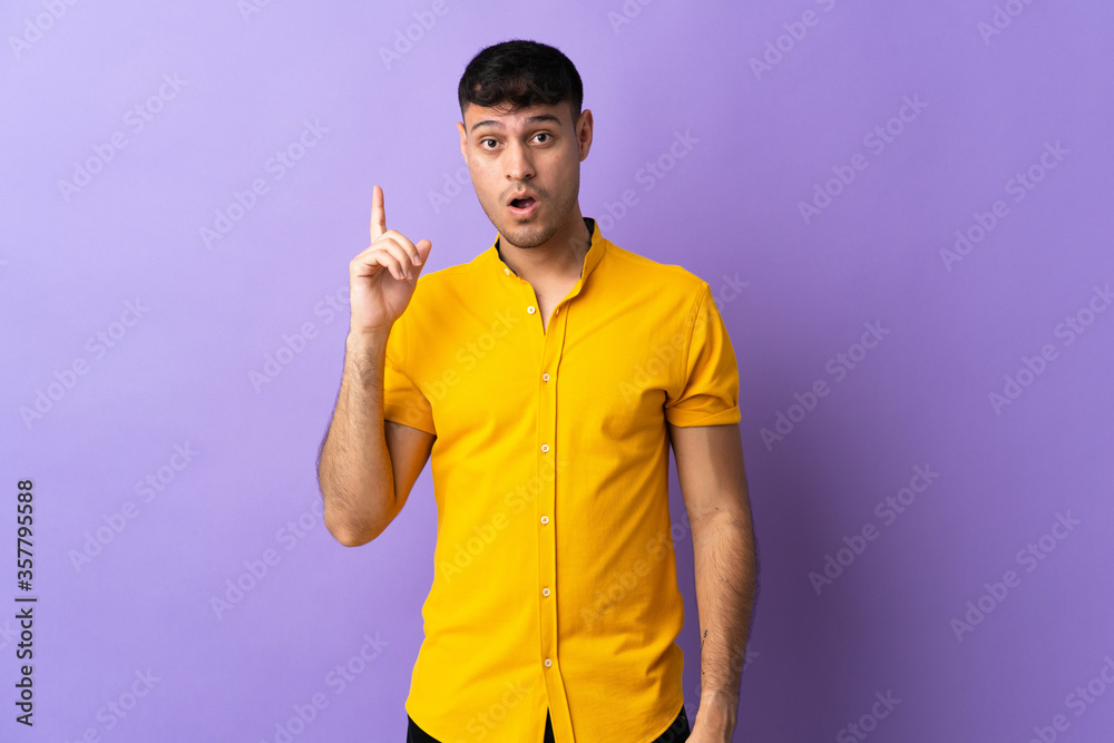 Young Colombian man isolated on purple background intending to realizes the solution while lifting a finger up Young Colombian man isolated on purple background intending to realizes the solution while lifting a finger up