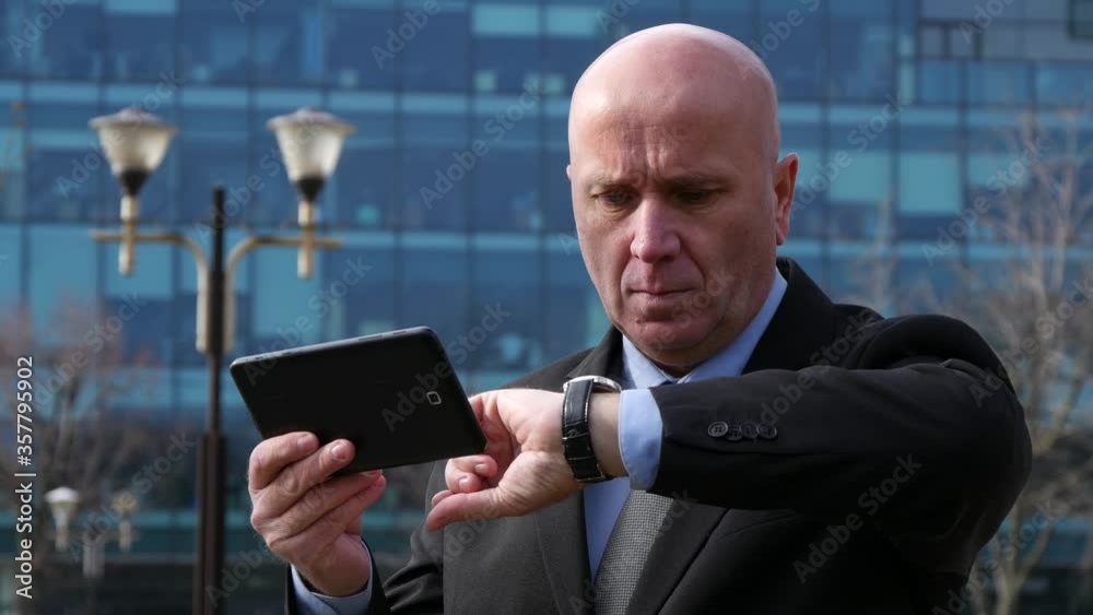 Businessman on the Street Checking Tablet Email and Looking to His Wristwatch Businessman on the Street Checking Tablet Email and Looking to His Wristwatch