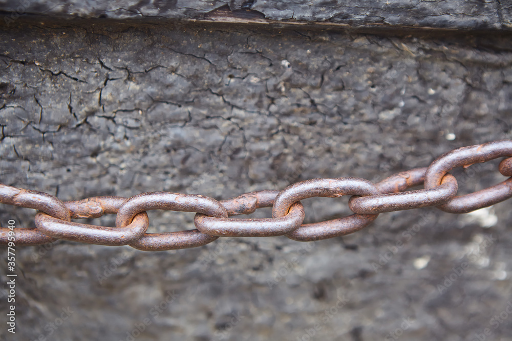 The anchor chain is stretched against the gray wall. Rusty metal The anchor chain is stretched against the gray wall. Rusty metal