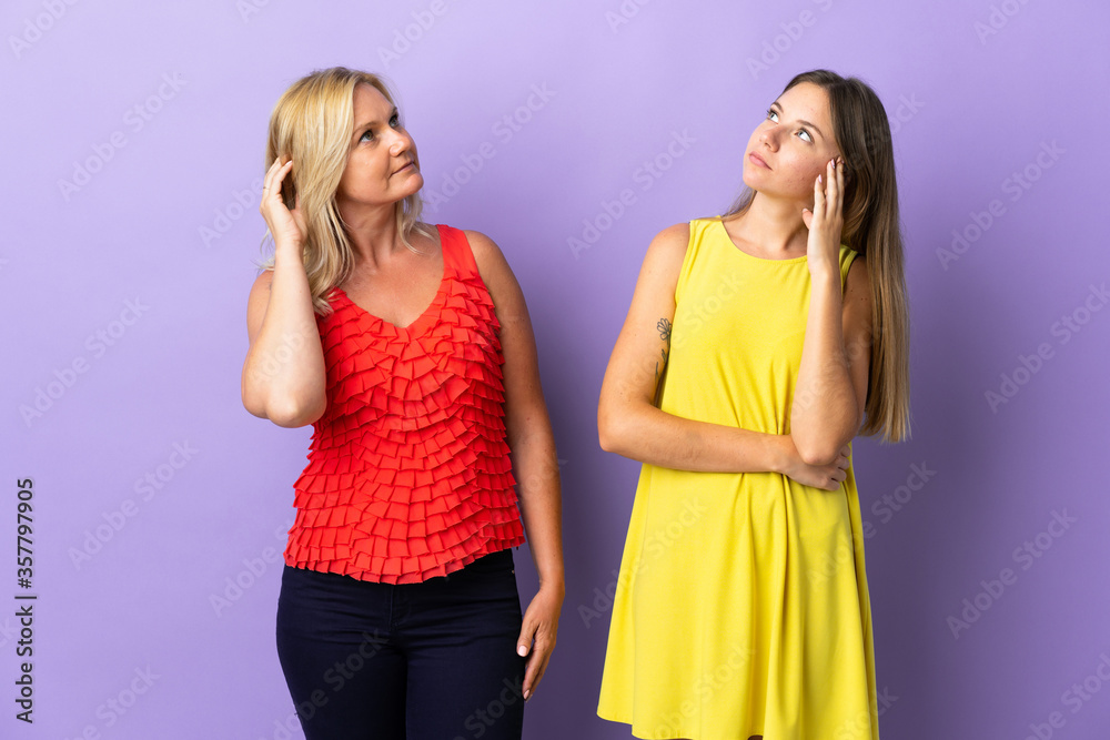 Mom and daughter isolated on purple background thinking an idea while scratching head Mom and daughter isolated on purple background thinking an idea while scratching head