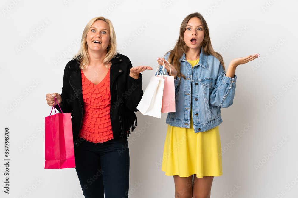 Mom and daughter buying some clothes isolated on white background with surprise and shocked facial expression