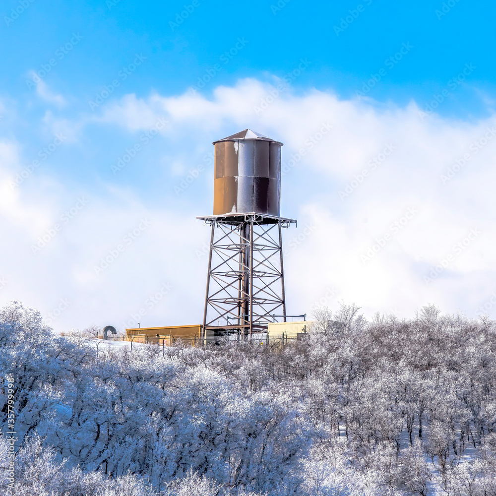 Obraz premium Square Water tank storage container on a tower at the snowy slope of Wasatch Mountains